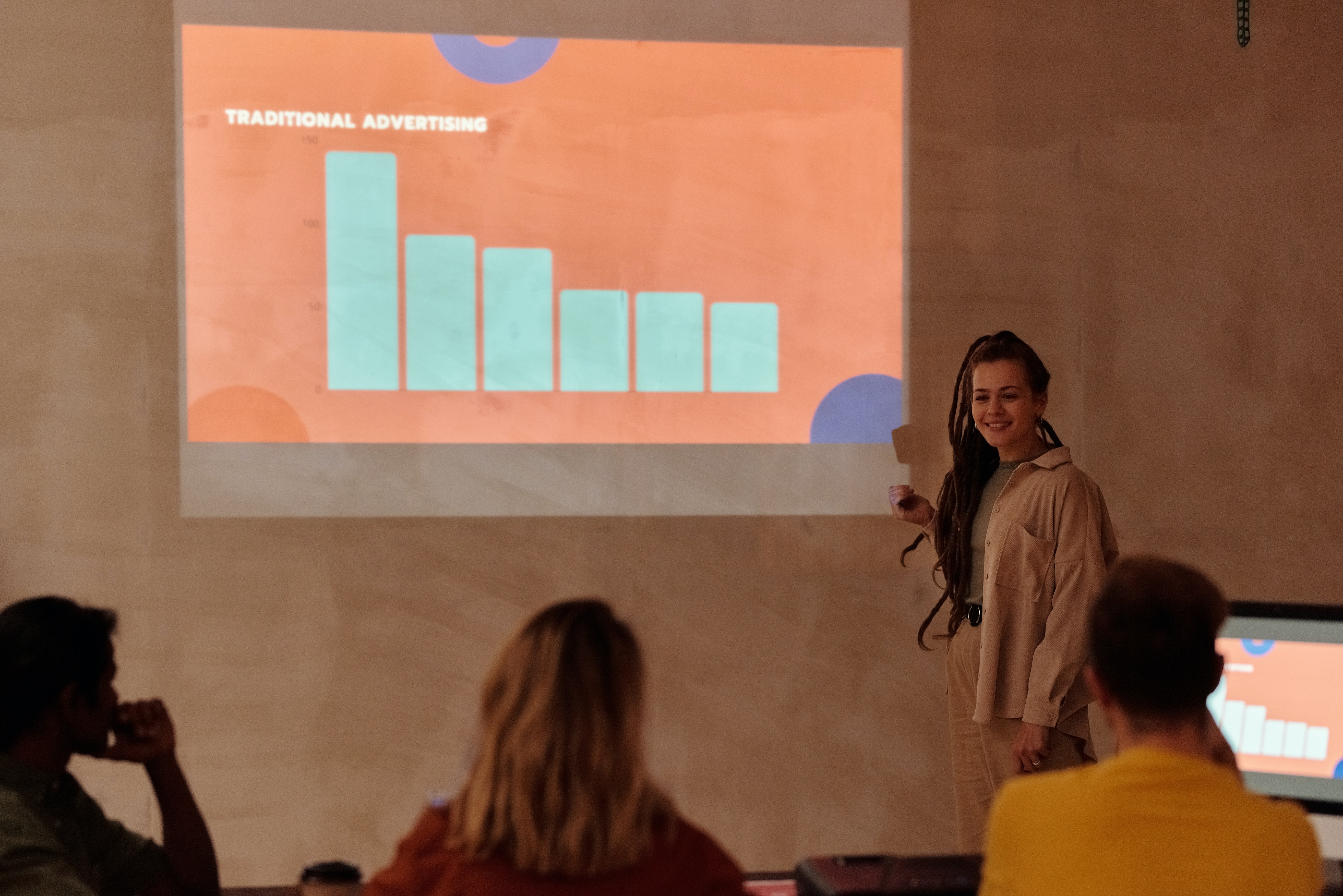 Young woman showing a graph on a presentation slide to a room of people